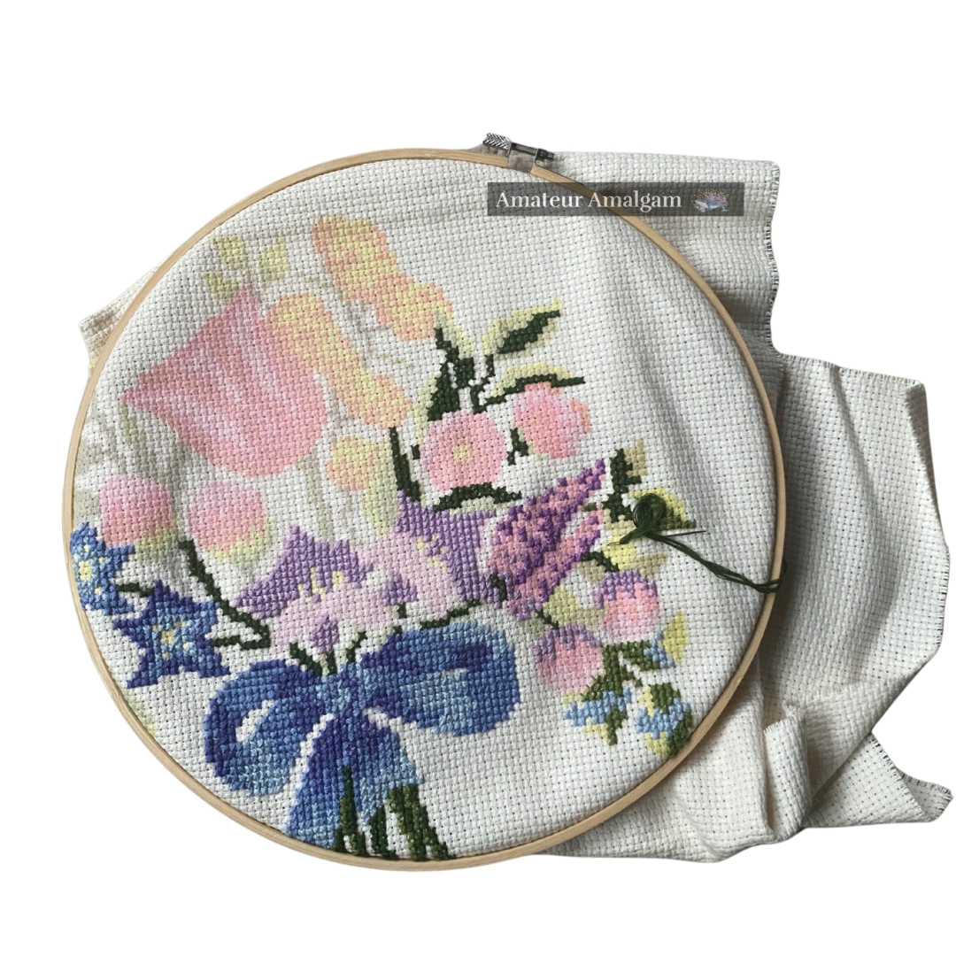 Embroidery hoop with a bouquet of flowers tied by a blue ribbon as the image being embroidered onto the fabric.