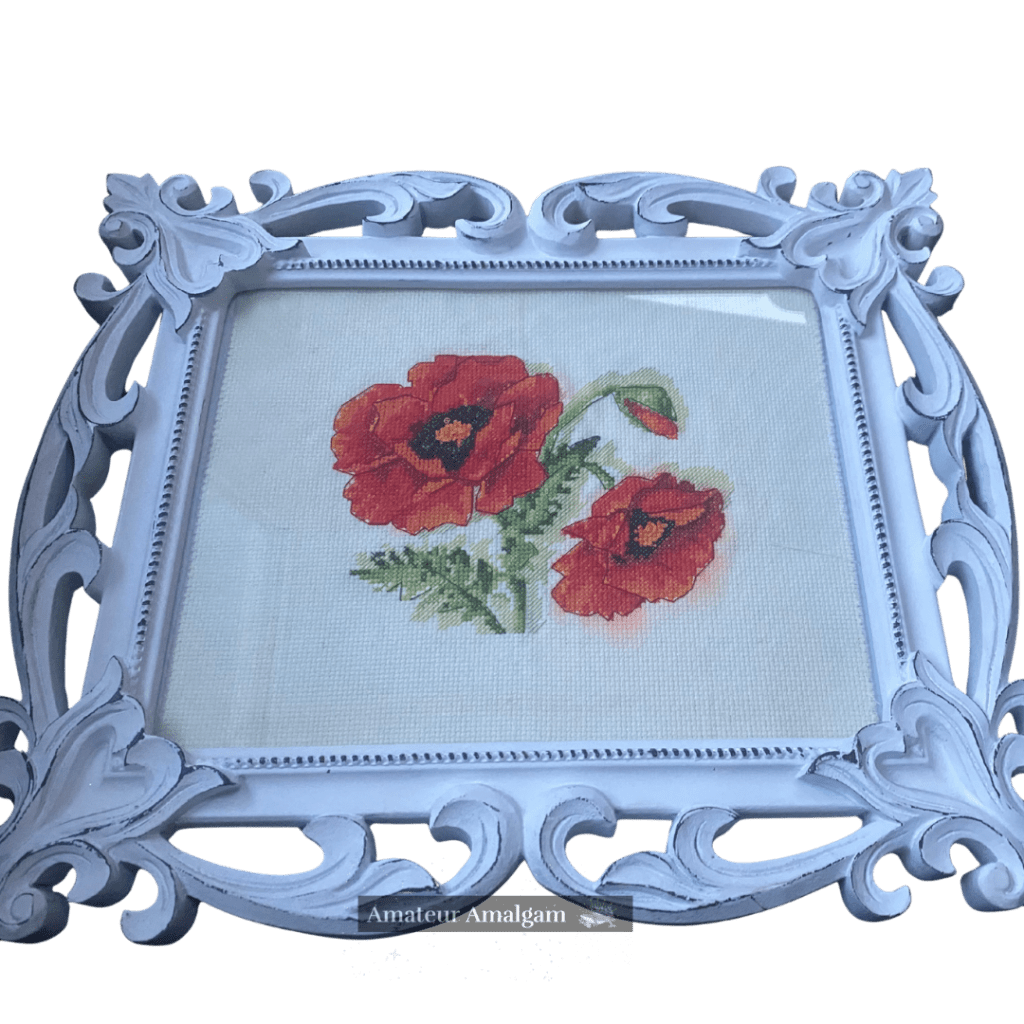 Framed image of a pair of red poppy flowers done in cross stitch