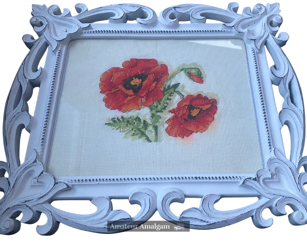 Framed image of a pair of red poppy flowers done in cross stitch